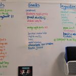 The freezer portion of a fridge/freezer with whiteboard sticker and a long list separated into meals, snacks and ingredients